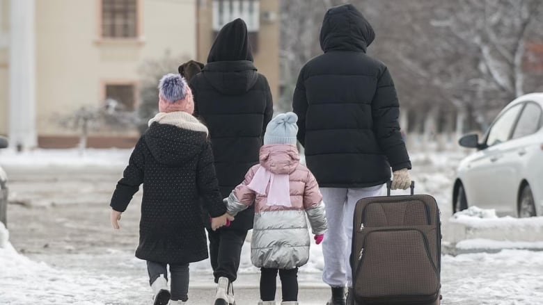 People walk in the street carrying bags.