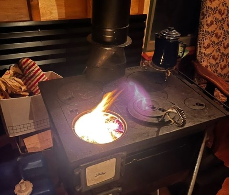 An old stove with a flame coming out of one of the burners. 