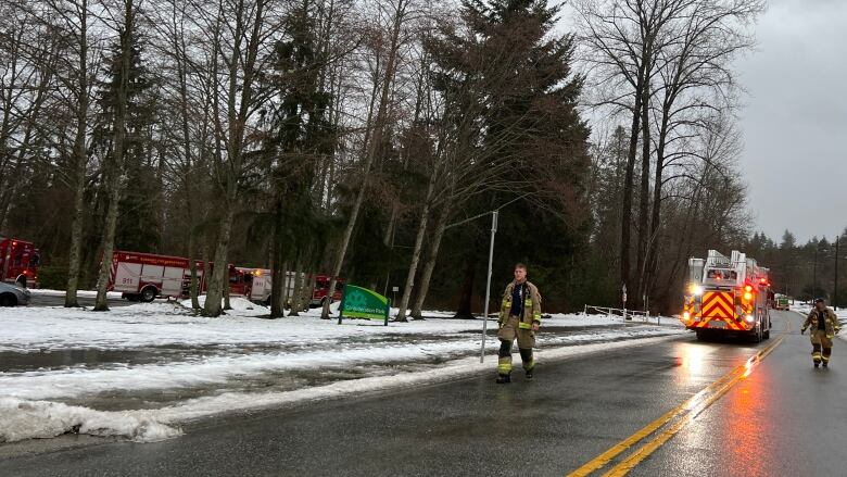 Firefighters walk along a snowy road.