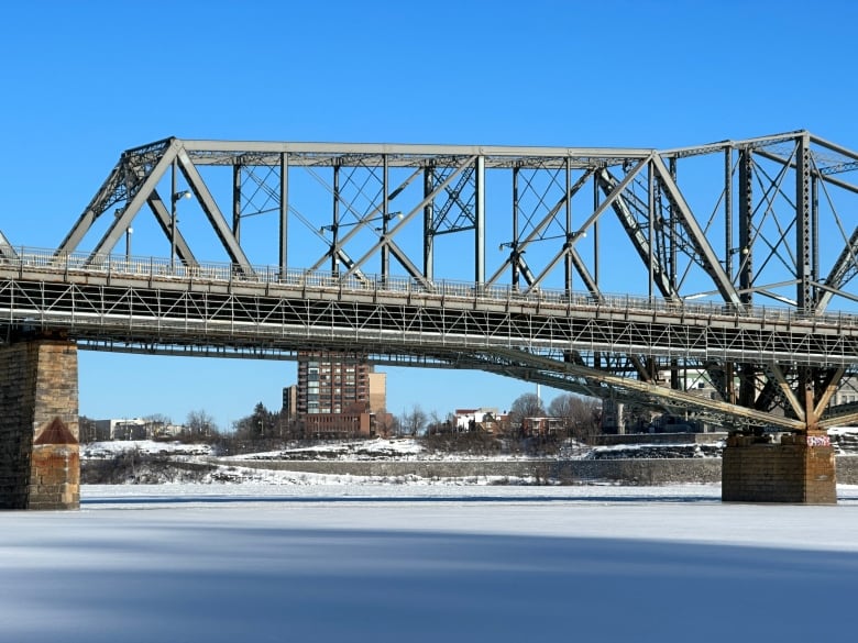 A steel bridge over a city river in winter.