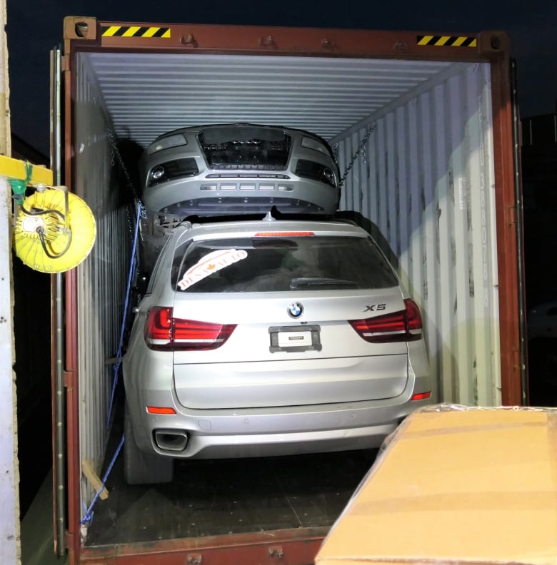 Two cars are seen in what appears to be a shipping container.