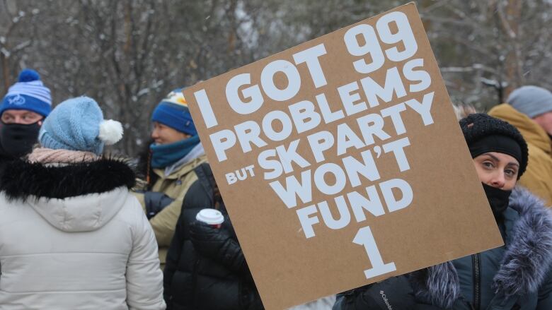 A woman holds a sign with the phrase 