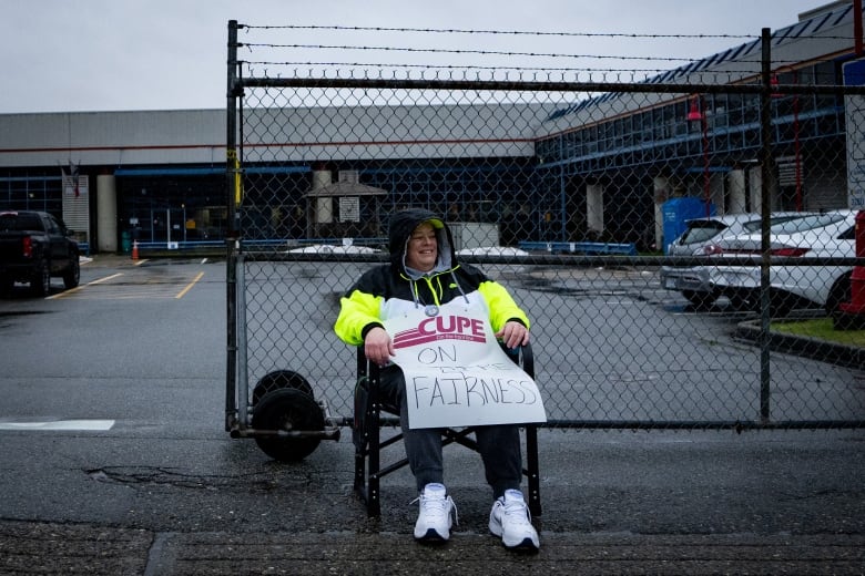 A transit worker from the Canadian Union of Public Employees Local 4500 sits in the rain during a strike in Burnaby, B.C., on Monday, Jan. 22, 2024. 