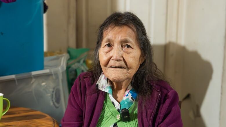 Elder in a purple sweater sits at a kitchen table