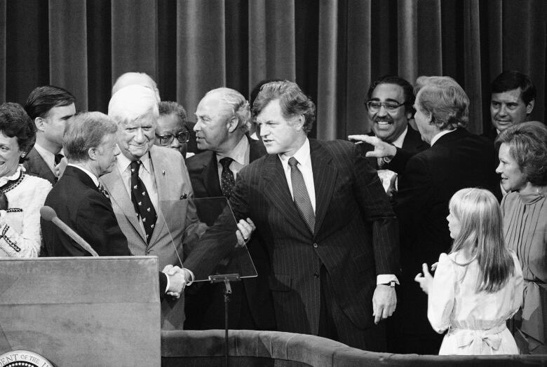 Carter at podium, left, shakes hands with Kennedy