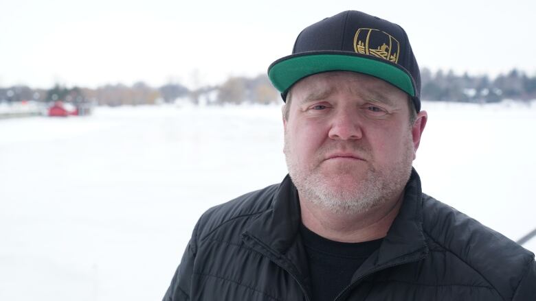 A business owner poses for a photo in front of a frozen body of water.