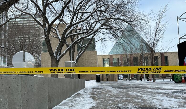 Yellow police tape outside a building topped with a glass pyramid.