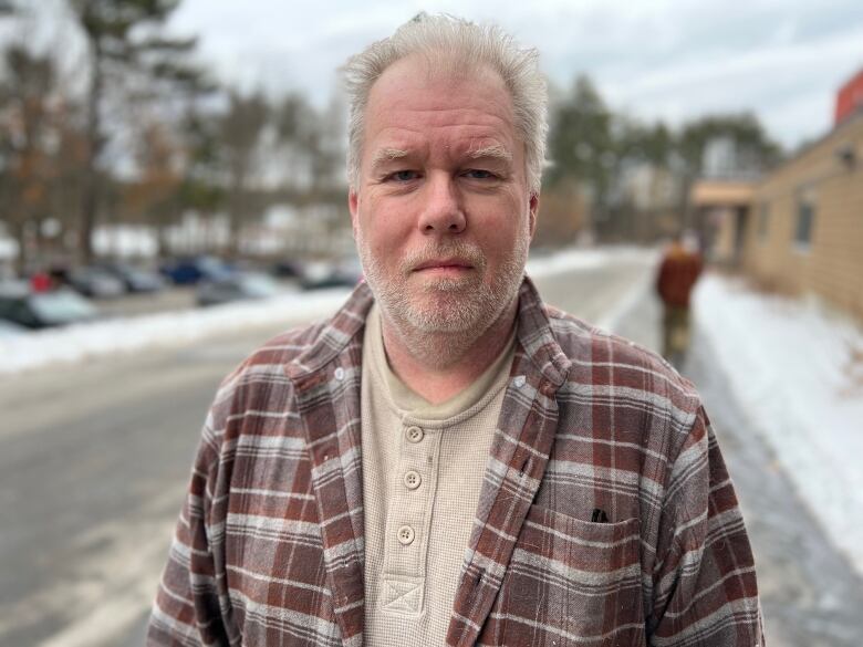 Profile picture of man in flannel checkered shirt, with trees in background