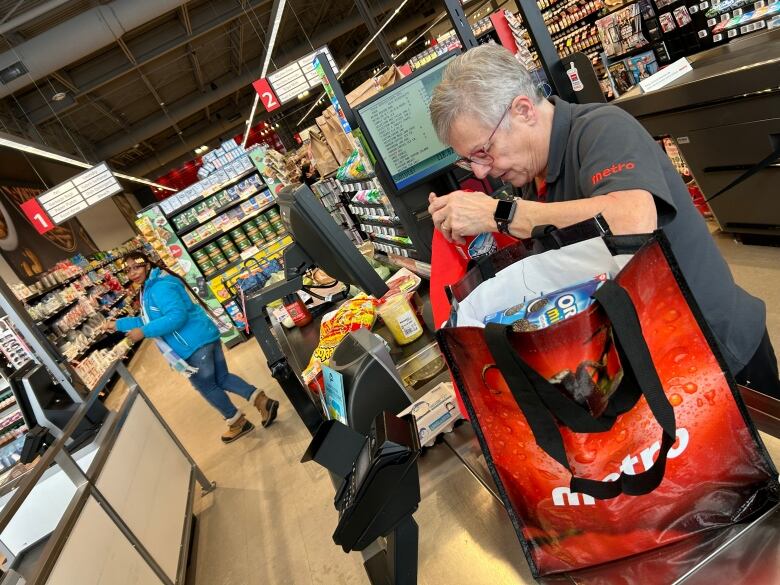 A grocery store employee works a checkout counter.