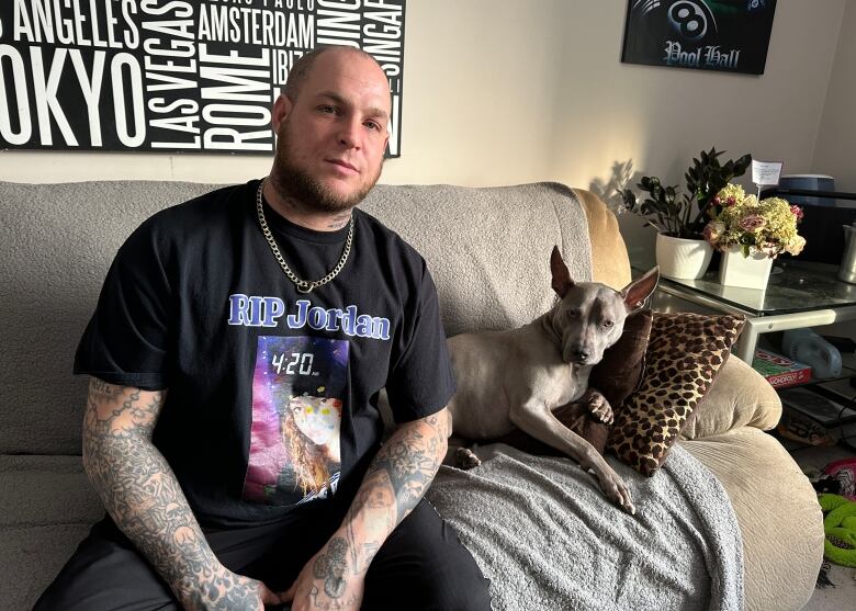 A man sits with a dog on a couch.