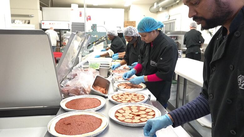 Pizza is being prepped at a restaurant kitchen. 