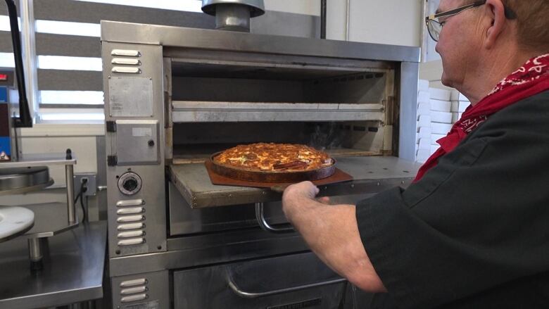 A hot Regina-style pizza is taken out of the oven.