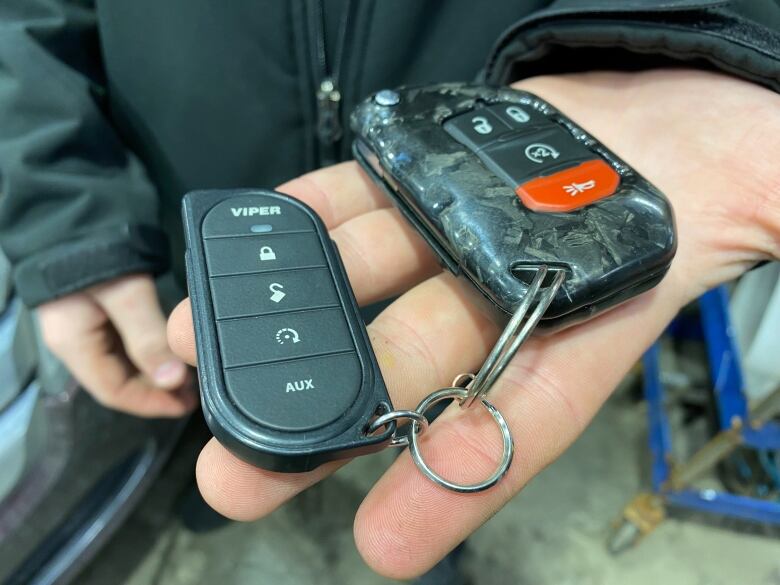 Someone holds two vehicle fobs.