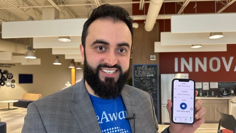 A man holds a phone while smiling.