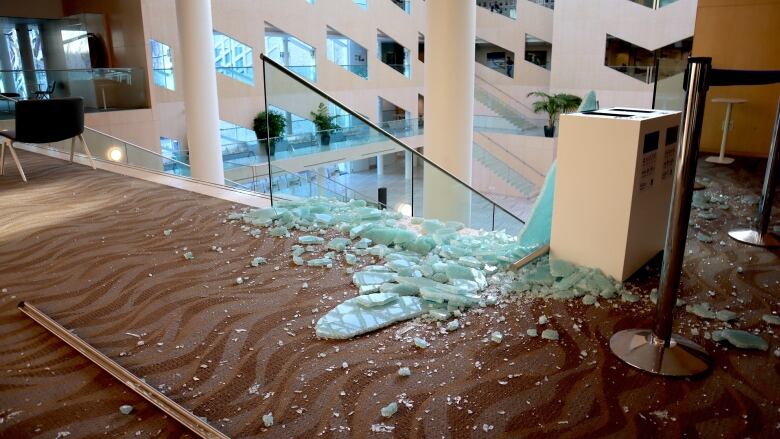 Piles of smashed glass on a carpted floor inside a building with many windows.