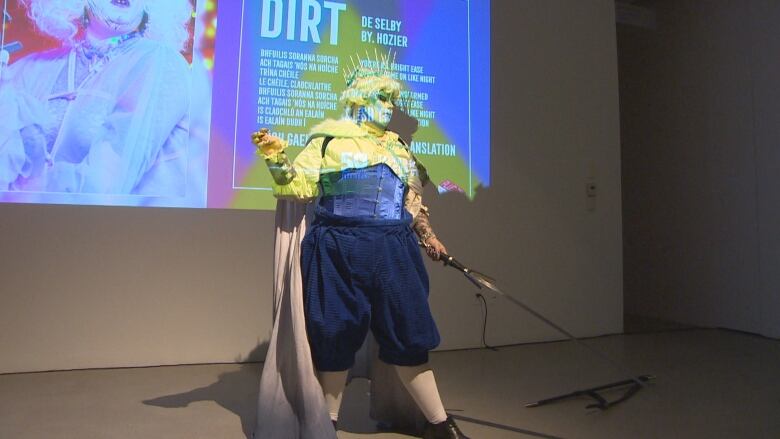 A drag artist performs while wearing a crown and carrying a sword. 