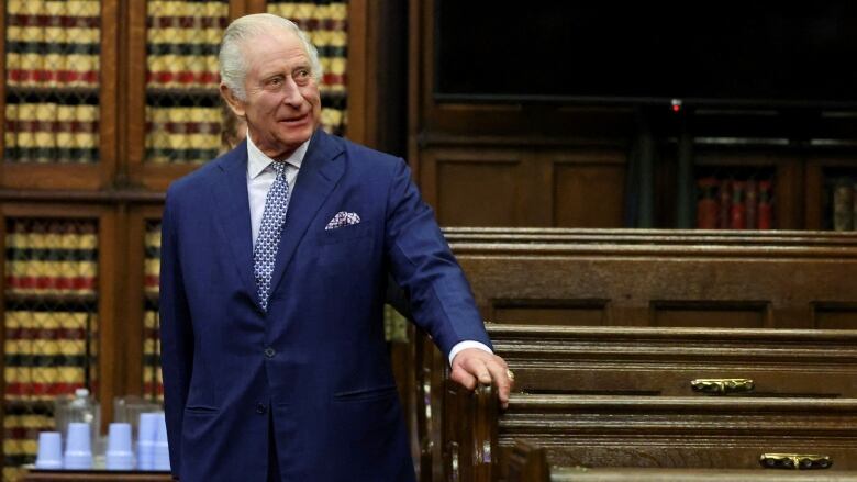 King Charles, wearing a blue suit, visits a court room in London, England.