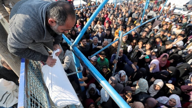 A Palestinian man holds a flour bag as others wait to receive theirs from the United Nations Relief and Works Agency.