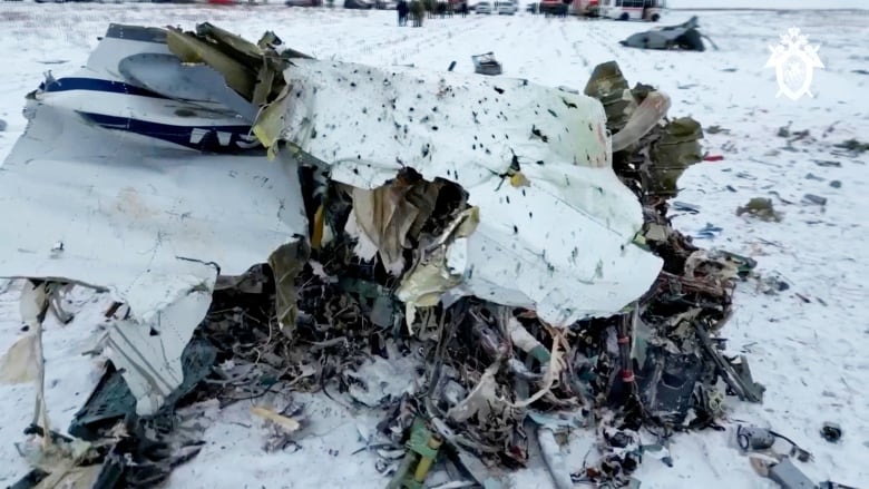 A large piece of machinery or debris is shown on a snowy field in closeup.