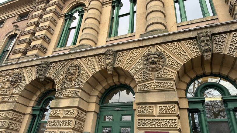 A sandstone courthouse building is shown showing arched windows and green doors and trim.