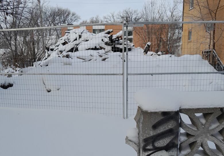 A pile of rubble can be seen behind a fence.