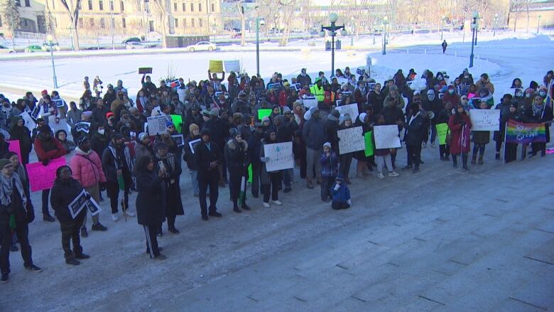 People gather outside with signs.