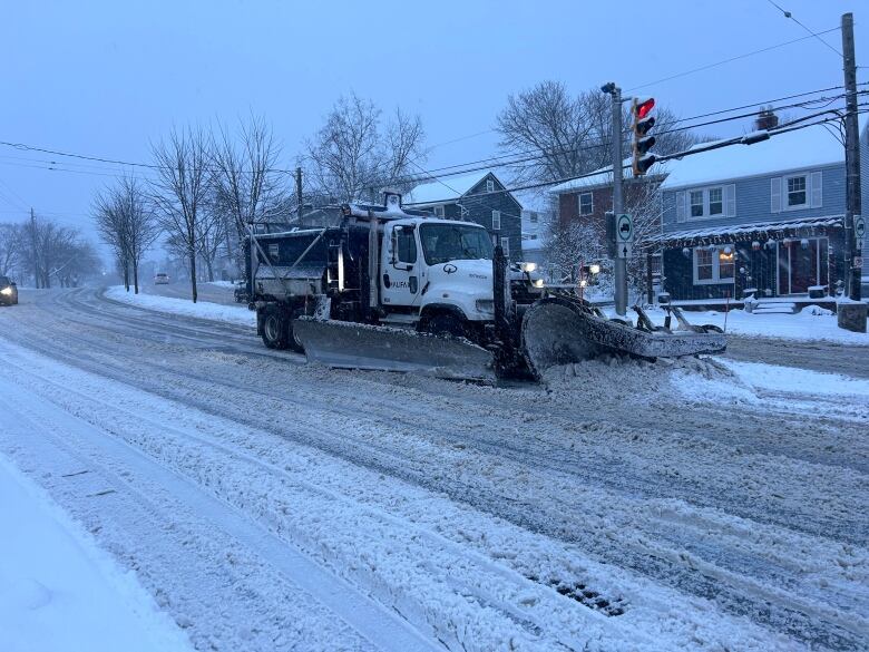 A plow drives down a snow-covered street.