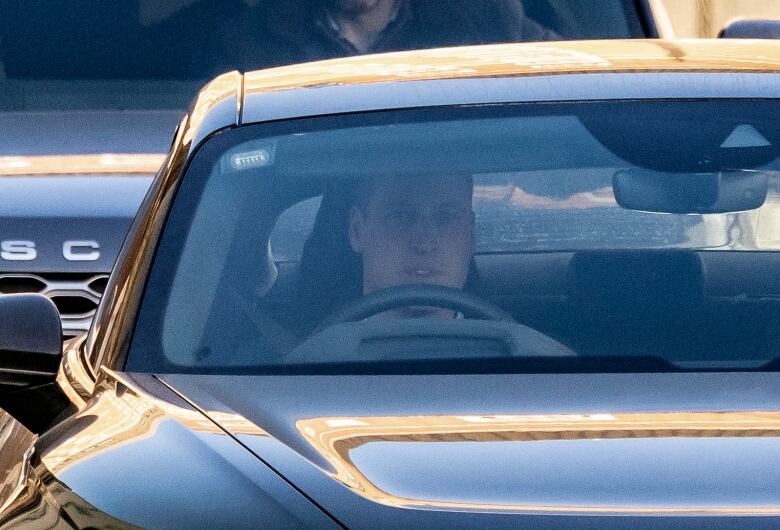 A man is shown at the wheel of a vehicle through the front windshield.