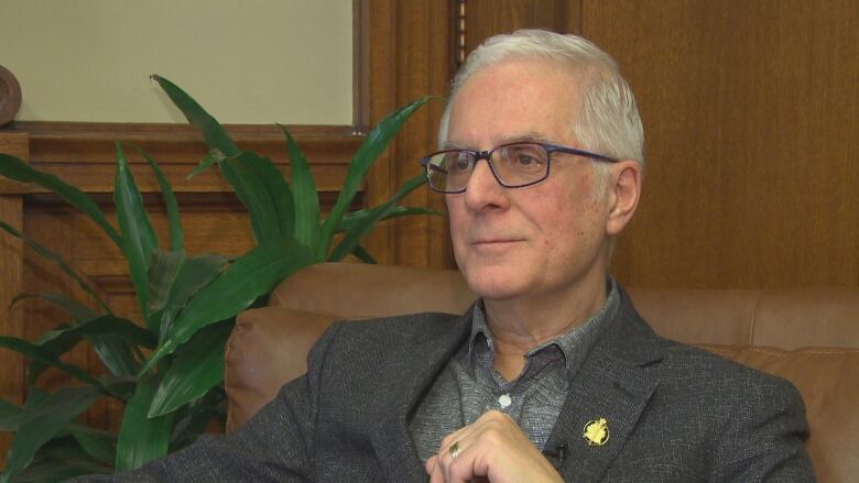 A portrait of a man with grey hair and glasses