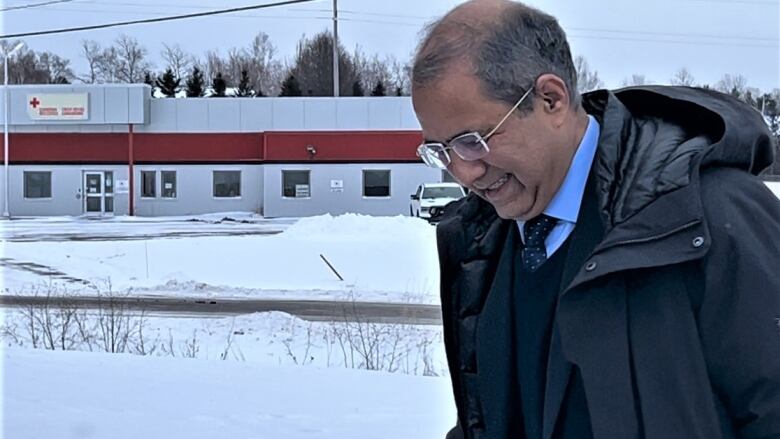 Balding man with glasses walking outside in winter.