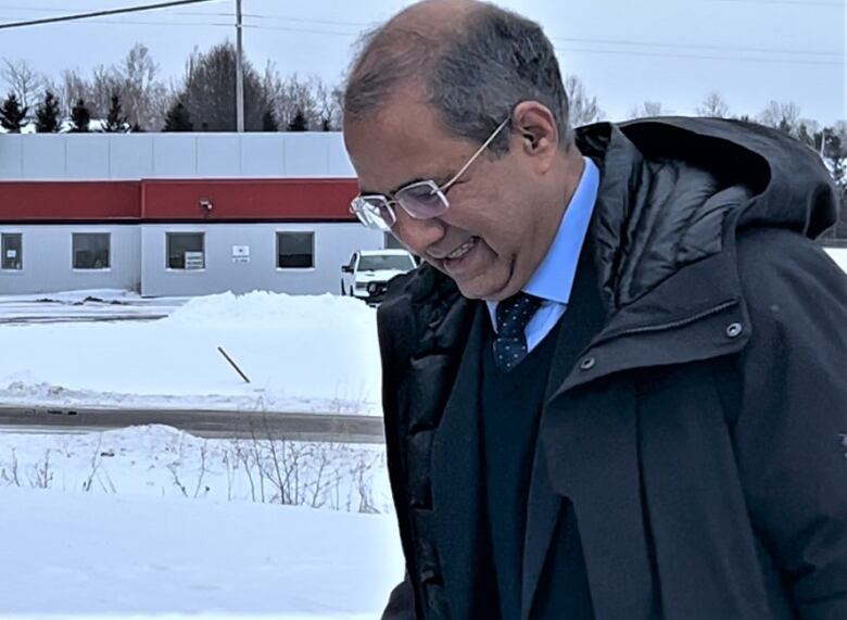 Balding man with glasses walking outside in winter.