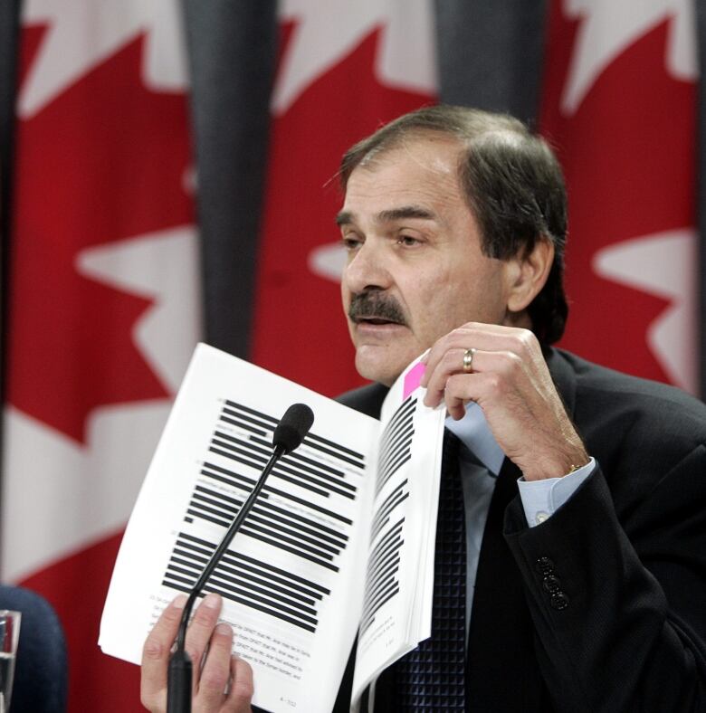 Paul Cavalluzzo, lead commission council for the Arar inquiry, holds up a copy of documents that have been blacked-out for security reasons at a news conference in Ottawa Monday Dec. 20, 2004. The Canadian Security Intelligence Service clashed with the Foreign Affairs Department over a proposed letter intended to free Arar from the Syrian prison, information disclosed Monday by the federal inquiry into the Ottawa mans case shows.