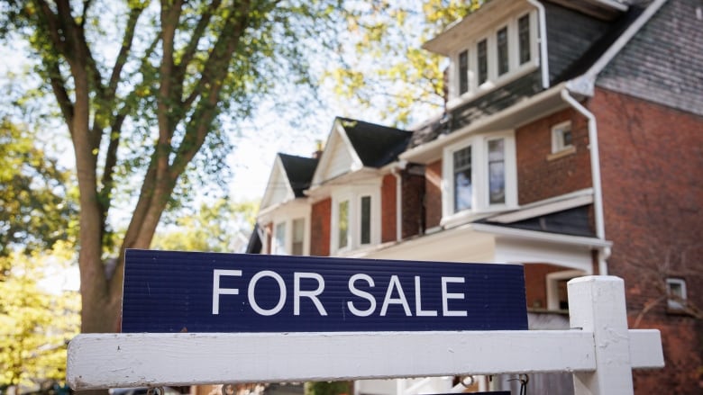 A for sale sign in front of a detached home.