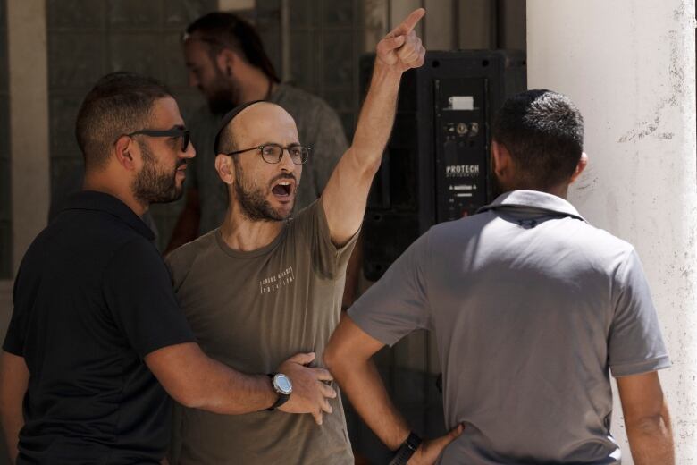 A man wearing a yarmulke shouts at protesters.