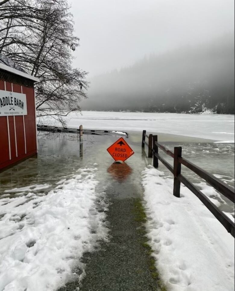 An orange 'Road Closed' sign sits on a flooded walkway in Pemberton, B.C.