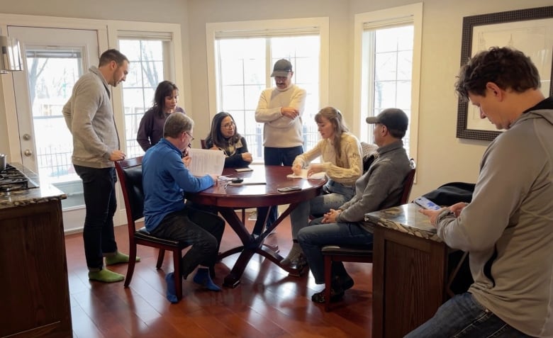 Eight owners at the River Run townhouse complex sit around a kitchen table to discuss a lease arrangement with the city of Calgary. 