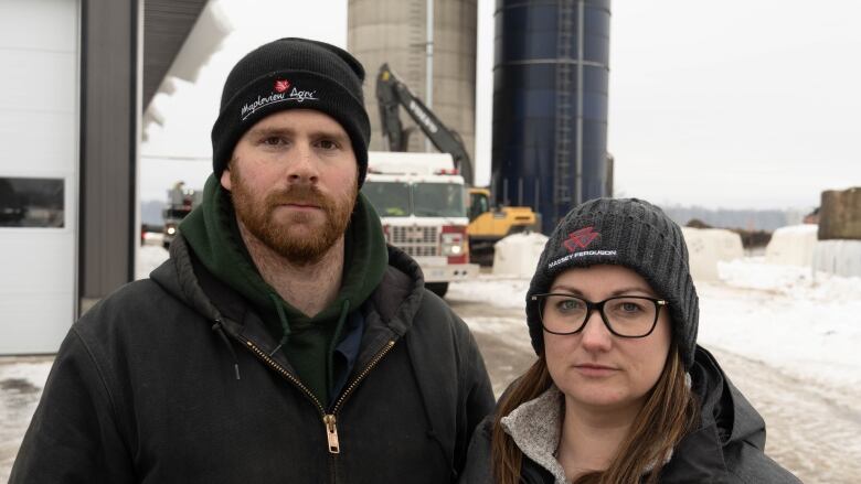 Spencer Hill and his wife Brittany Hill pictures at Hill Isle Farms, as firefighters work in the background. 