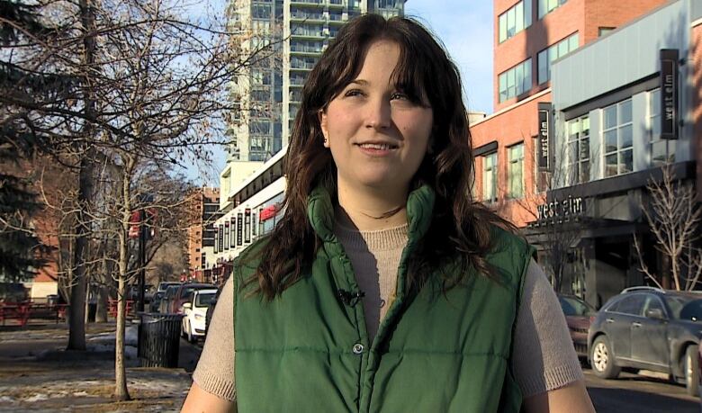 A woman with brown hair and a green vest.