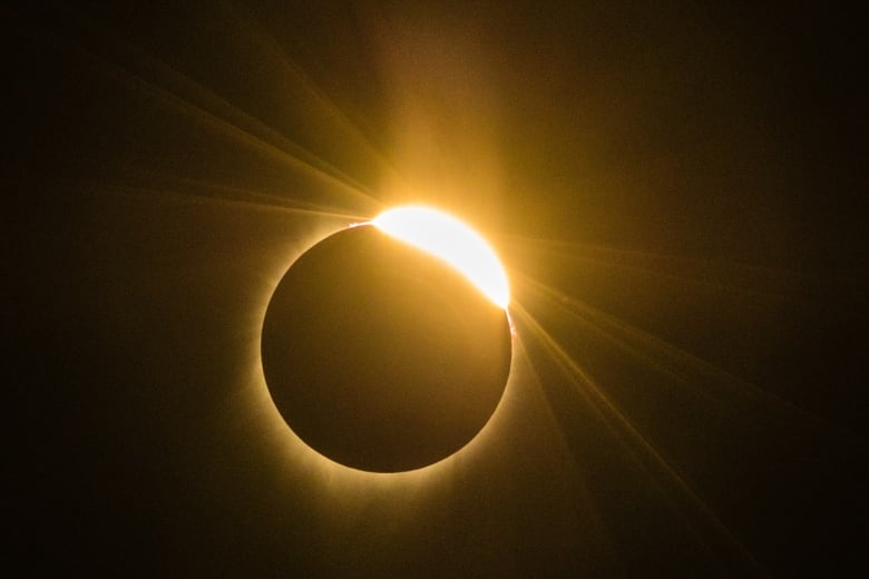 Black sky with orange ring of light as the sun is eclipsed by the moon.