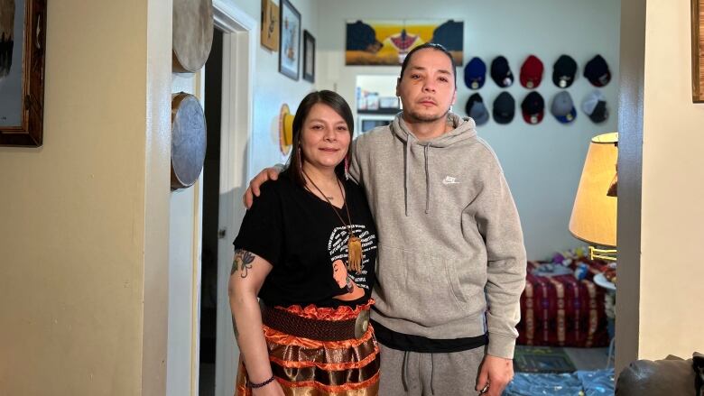 A middle-aged brother and sister look at the camera while standing next to each in a door frame.