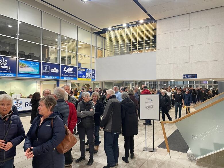 A crowd of people fill a lobby at a sports arena.