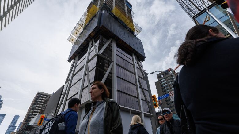 People walk past an under-construction condominium building.