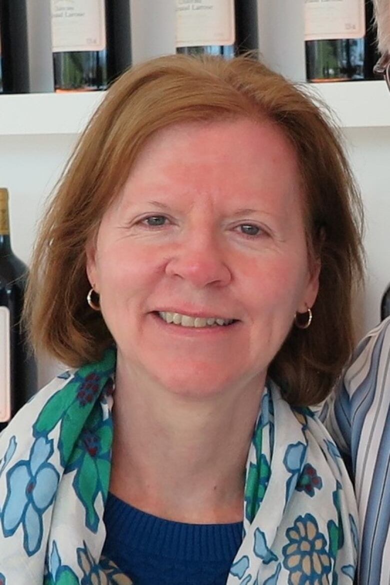 A portrait of a white woman with red hair. She is wearing a blue and white scarf.