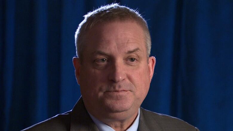 A man in a suit sitting down for a TV interview