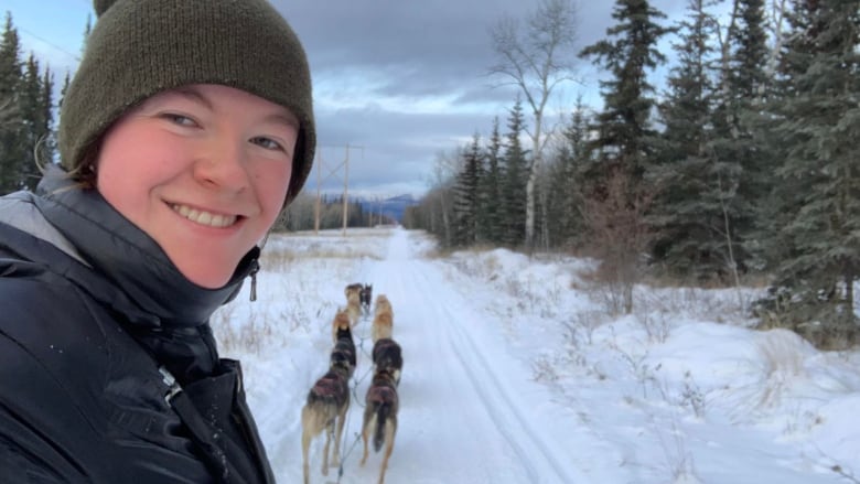 A woman poses for a selfie on a dog sled.