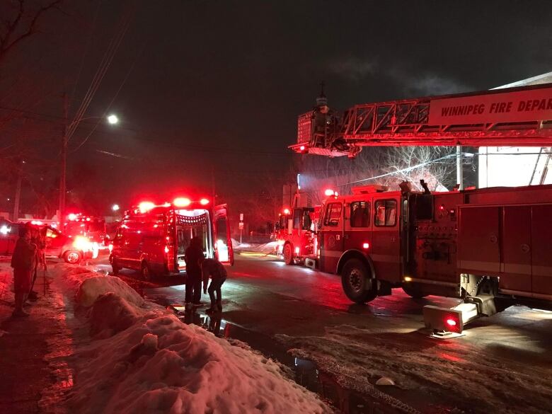 Fire trucks sit on a street at night.