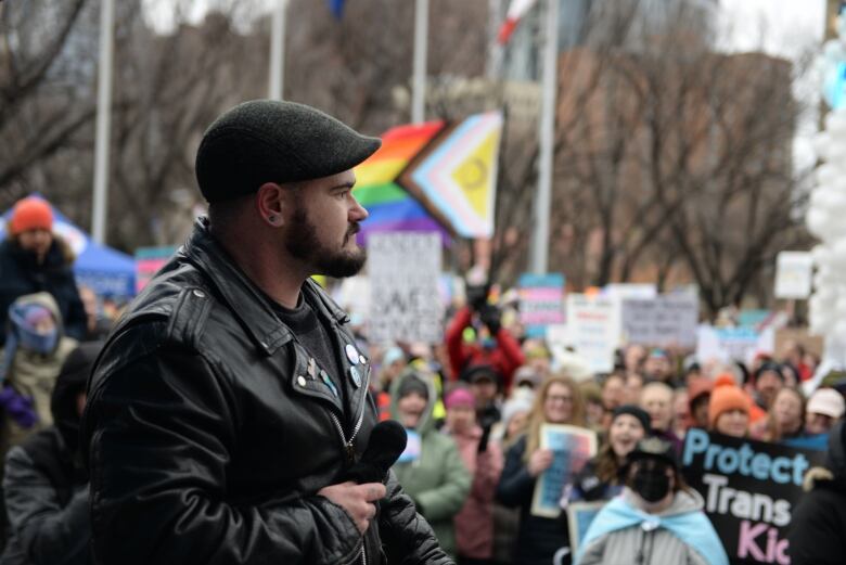 A man holds a microphone and wears a leather jacket. 