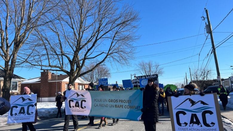 People stand in the street with banners.