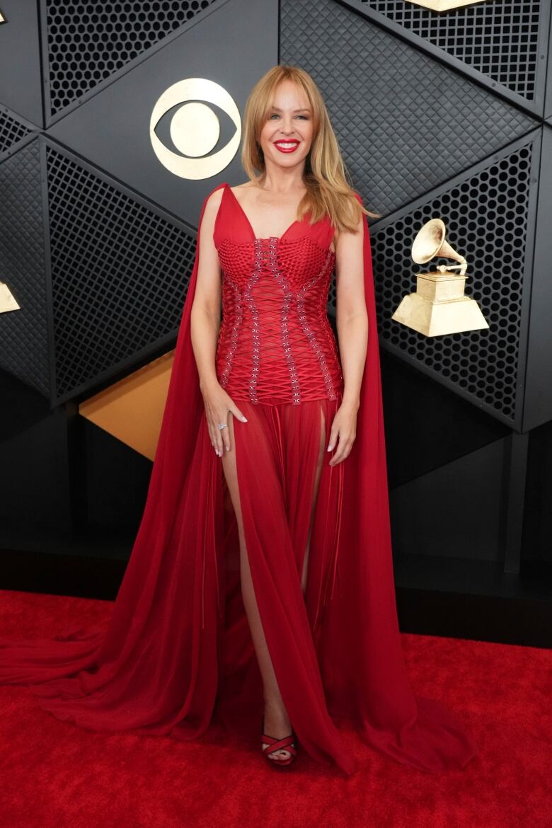 A woman wears a red dress with a corset and cape.