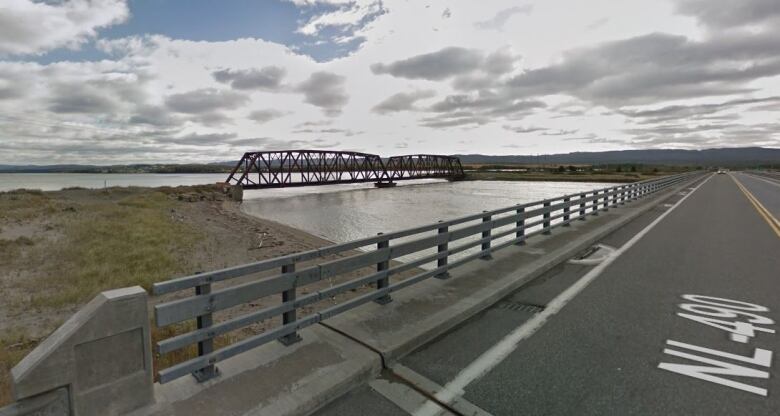 A old railway bridge crossing a river next to a newer highway bridge. 